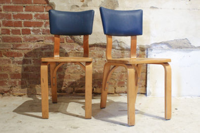 wooden chairs with blue leather tops in front of brick wall