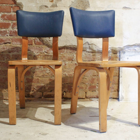 wooden chairs with blue leather tops in front of brick wall