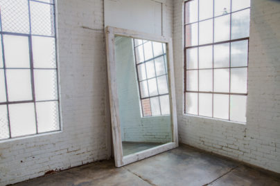 large white wooden mirror leaning against wall