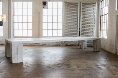 large white wooden table without bench in an empty warehouse room